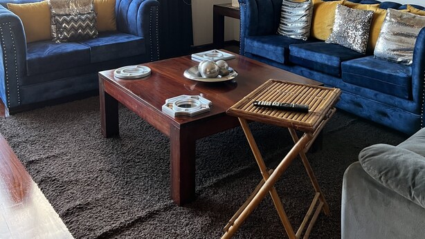 Una sala de estar moderna con dos sofás azules, una mesa de centro de madera y un cuadro en la pared.