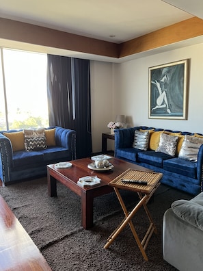 Un salon moderne avec deux canapés bleus, une table basse en bois et un tableau accroché au mur.