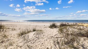 Une plage de sable avec des dunes et une végétation clairsemée.