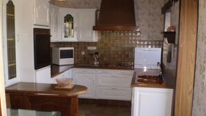 Una cocina compacta con armarios blancos, un microondas, una estufa y un lavabo.