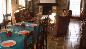 Un comedor con chimenea de ladrillo, sofás a rayas y una mesa de comedor para cuatro personas.