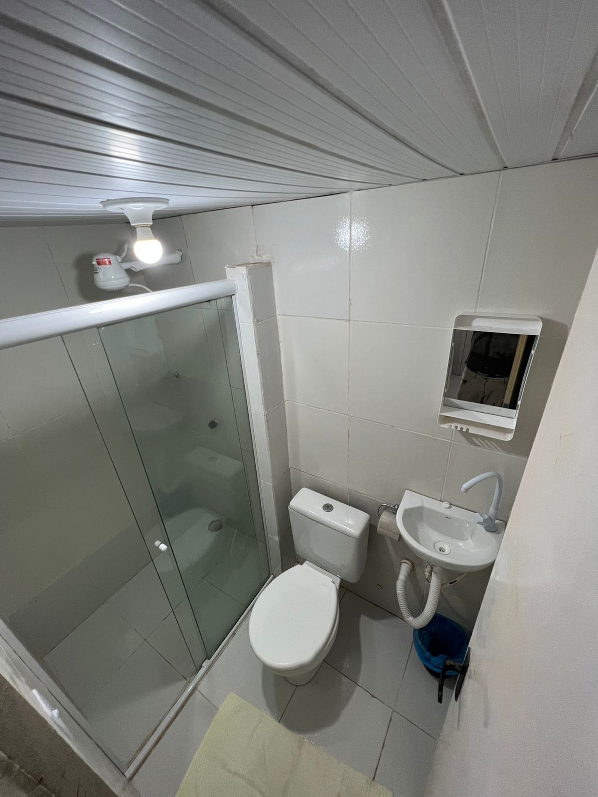 A bathroom with a glass shower enclosure, a toilet, a sink, and a small medicine cabinet.
