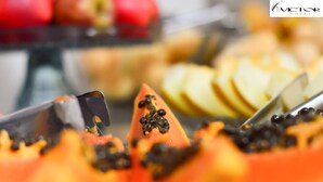 A close-up of a fruit display with papaya and sliced apples. - Victor Hotel (Patos de Minas)