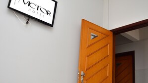 A hotel room with a bed, a wooden door, and a sign on the wall. - Victor Hotel (Patos de Minas)