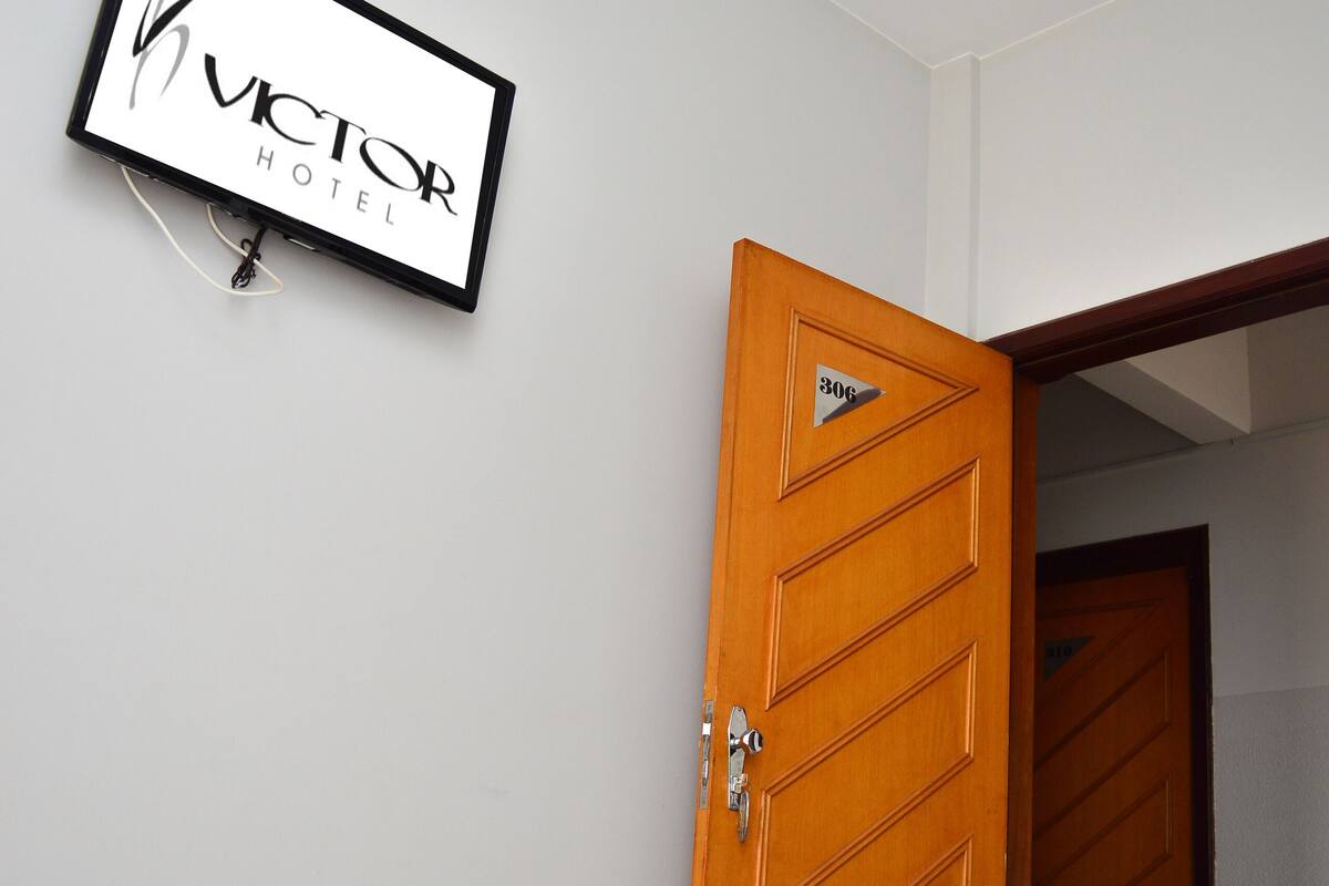 A hotel room with a bed, a wooden door, and a sign on the wall.