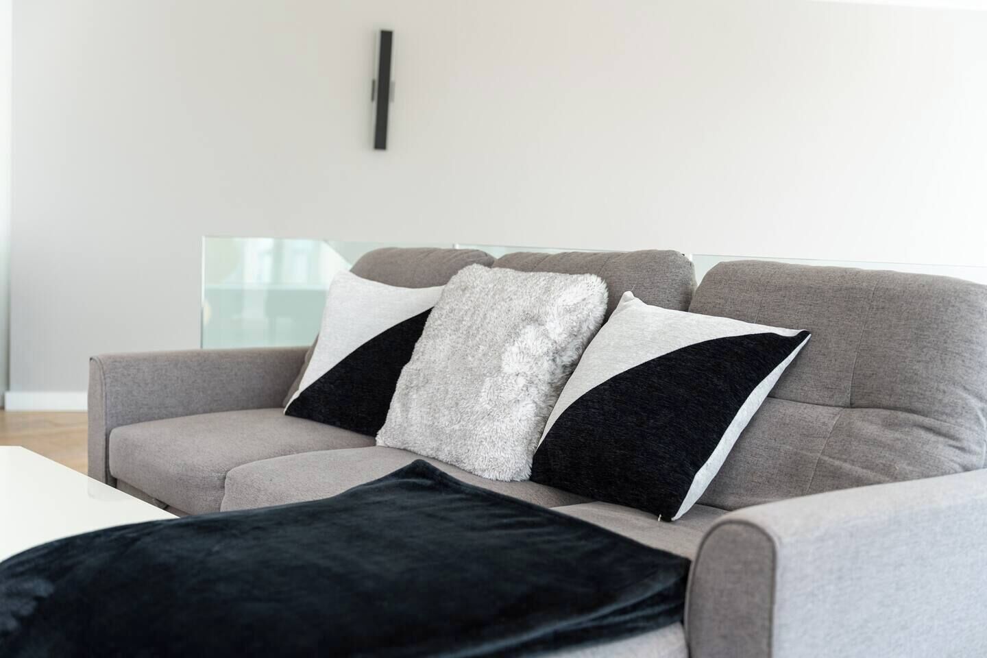 En grå soffa med tre kuddar i färgerna svart, vitt och grått.