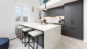 Een moderne keuken met een groot kookeiland, barkrukken en donkere kastjes.