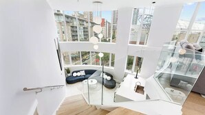 Een modern interieur met een glazen trap die leidt naar een zithoek met een bank en salontafel.