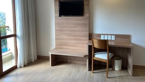 Ett modernt hotellrum med ett skrivbord och en stol i trä, samt en väggmonterad TV.