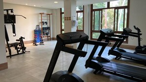 Ett gym med löpband, styrketräningsmaskiner och ett ställ med hantlar.