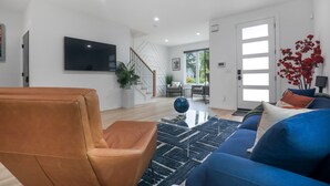 A modern living room with a brown leather chair, a blue sofa, and a black and white rug. - Modern Home with Rooftop Deck (Atlanta)