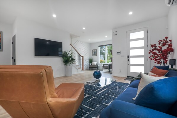 A modern living room with a brown leather chair, a blue sofa, and a black and white rug. - Modern Home with Rooftop Deck (Atlanta)