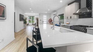 A modern kitchen with a central island, stainless steel appliances, and a black and white hexagonal backsplash. - Modern Home with Rooftop Deck (Atlanta)