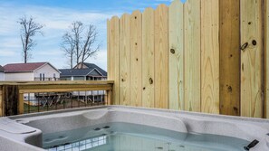 A hot tub with a wooden deck and a wooden fence in the background. - Cozy Hideaway • Hot Tub • Arcade Machine • Dogs OK (Sevierville)