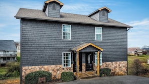 A two-story house with a stone foundation, a front porch, and a chimney.