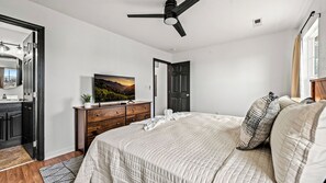 A bedroom with a bed, a dresser, a television, and a ceiling fan.