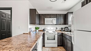 A kitchen with dark cabinets, a white stove, and a microwave.