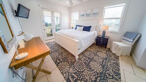 Une chambre à coucher comprenant un lit, un bureau, une chaise, un ventilateur de plafond et une fenêtre.