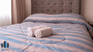 Una cama bien hecha con ropa de cama a rayas y dos toallas enrolladas.