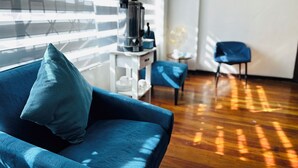 Una sala de estar moderna con un sofá azul, una cafetera sobre una mesita blanca y un sillón azul.