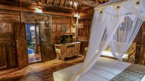 A rustic wooden room with a bed, a wooden dresser, and a television. - The Meranggi (Ubud)