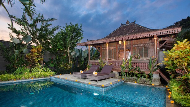 A pool area with two lounge chairs and a wooden structure with a tiled roof. - The Meranggi (Ubud)