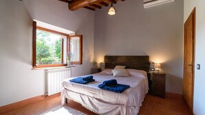 Une chambre avec un grand lit, une fenêtre donnant sur un paysage verdoyant, un radiateur et un plafond en bois.