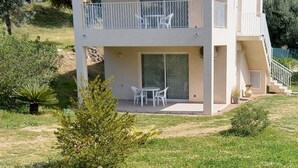 Ein zweistöckiges Gebäude mit einem Balkon, einer Terrasse mit Tisch und Stühlen sowie einer Treppe, die zu einer oberen Etage führt.