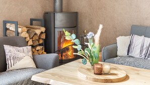 A cozy living room with a fireplace, a coffee table with a vase and candles, and a sofa with patterned cushions. - Le Coeur des Vosges -  Jacuzzi disponible toute l'année (Cornimont)