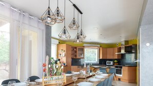 A modern kitchen with wooden cabinets, a built-in oven, and a dining area set for a meal. - Le Coeur des Vosges -  Jacuzzi disponible toute l'année (Cornimont)