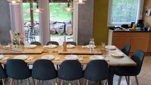 A dining area with a long wooden table set for six, surrounded by dark chairs. - Le Coeur des Vosges -  Jacuzzi disponible toute l'année (Cornimont)