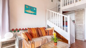 Un salón acogedor con un sofá, una mesita de centro y una escalera que sube a un nivel superior.