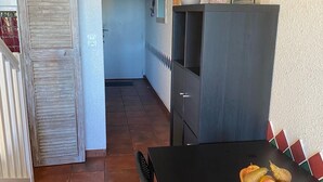 Un comedor con una mesa negra, dos sillas y un frutero. Un cactus está en un estante sobre la mesa.