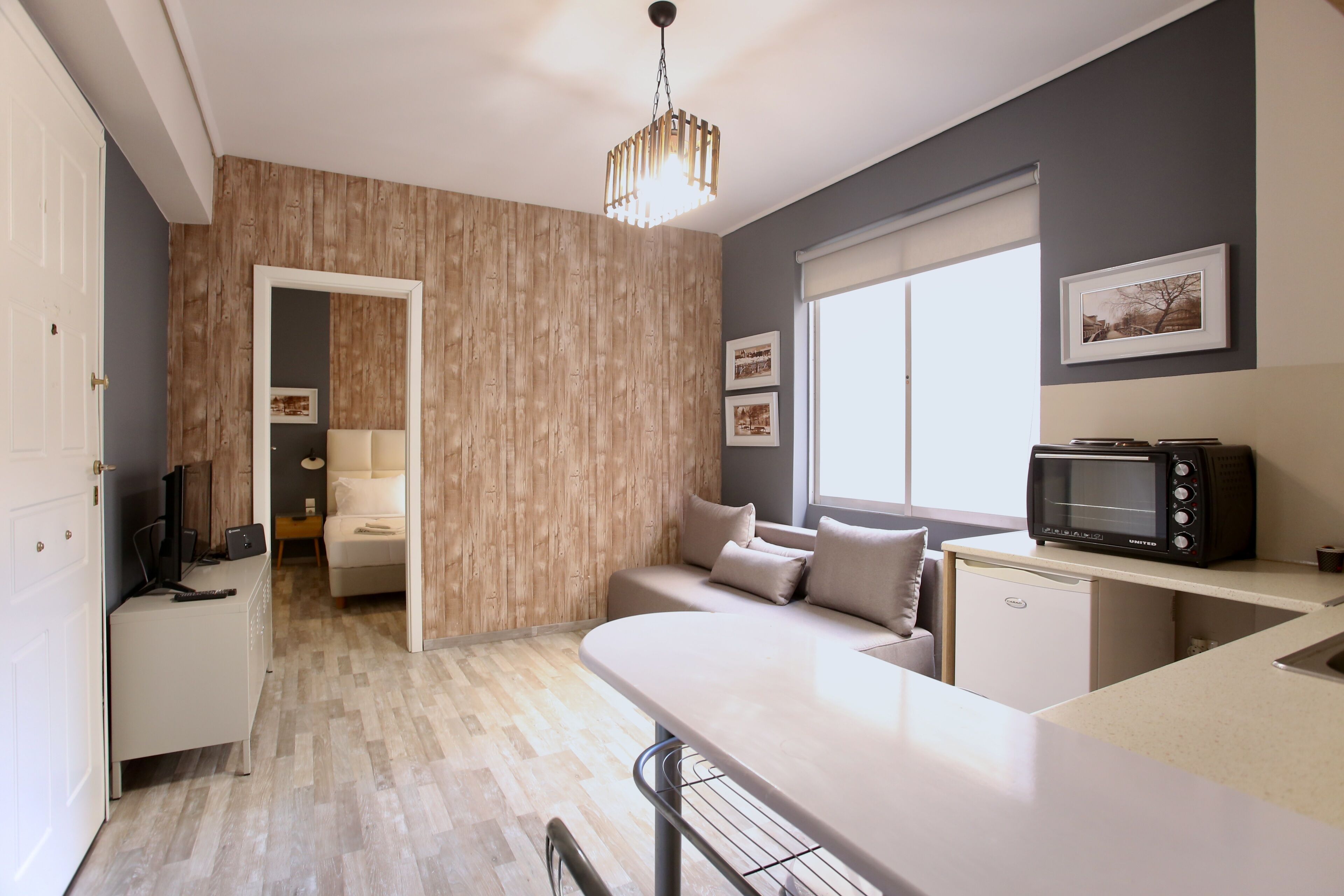 A modern kitchen with a microwave, a dining area with a bench, and a wooden accent wall.