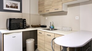 Una cocina compacta con microondas, pileta y un refrigerador pequeño.