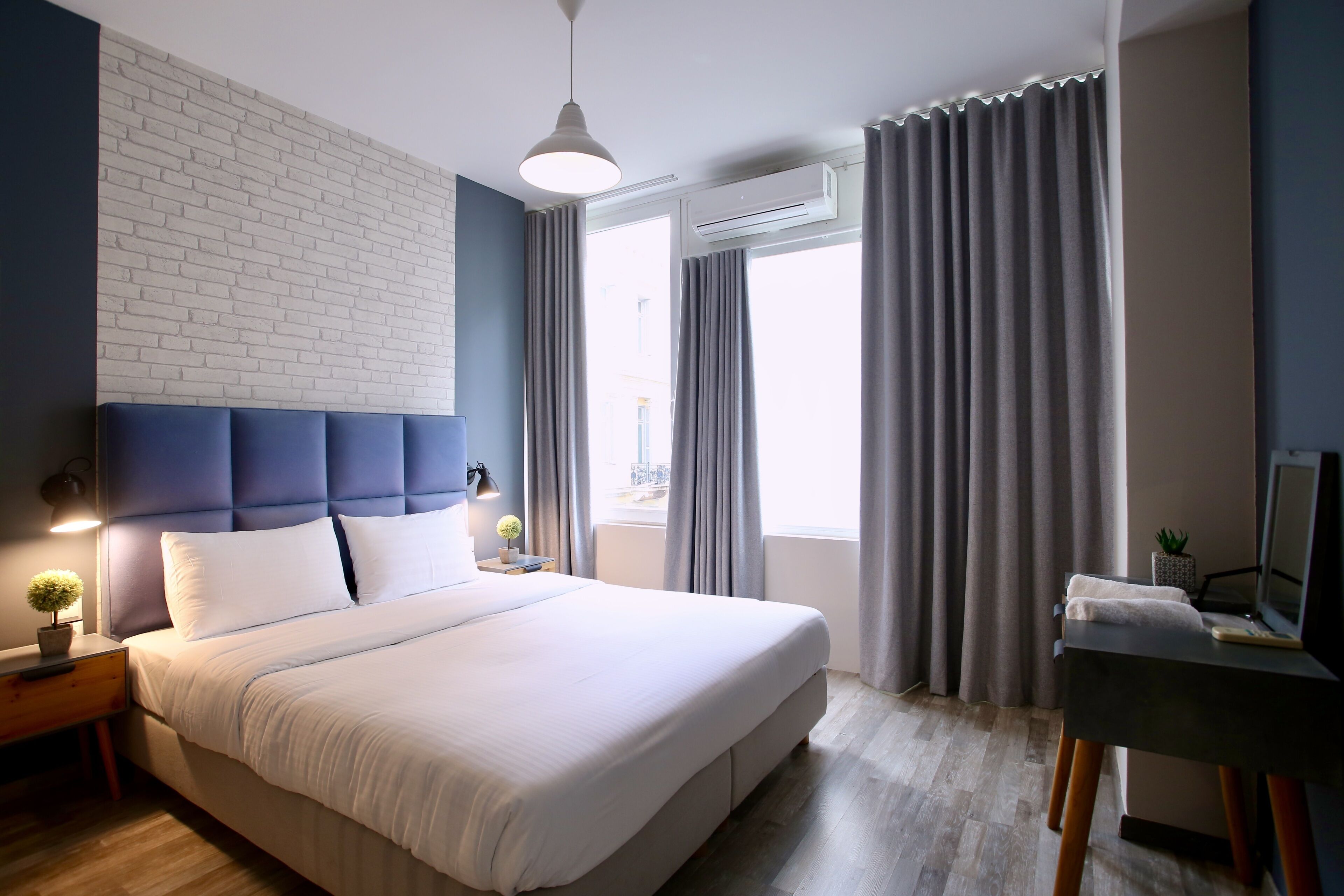 Une chambre d’hôtel moderne avec un grand lit, un bureau et une fenêtre avec des rideaux.