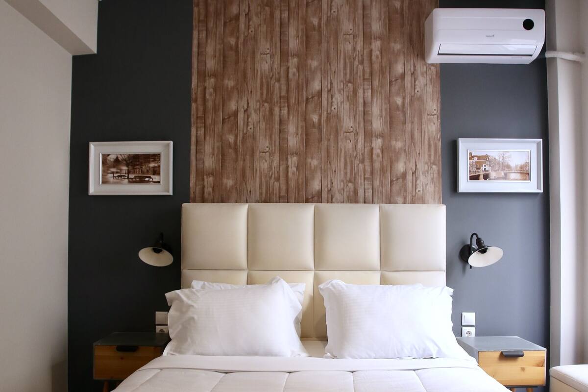 Una cama bien hecha con toallas dobladas, un panel de madera y una lámpara en el techo.