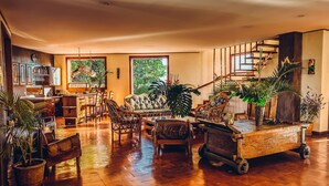 A spacious living area with a wooden floor, a sofa, chairs, a dining table, and a kitchen area with cabinets and a window. - Canal Grande Lodge (Piedades)
