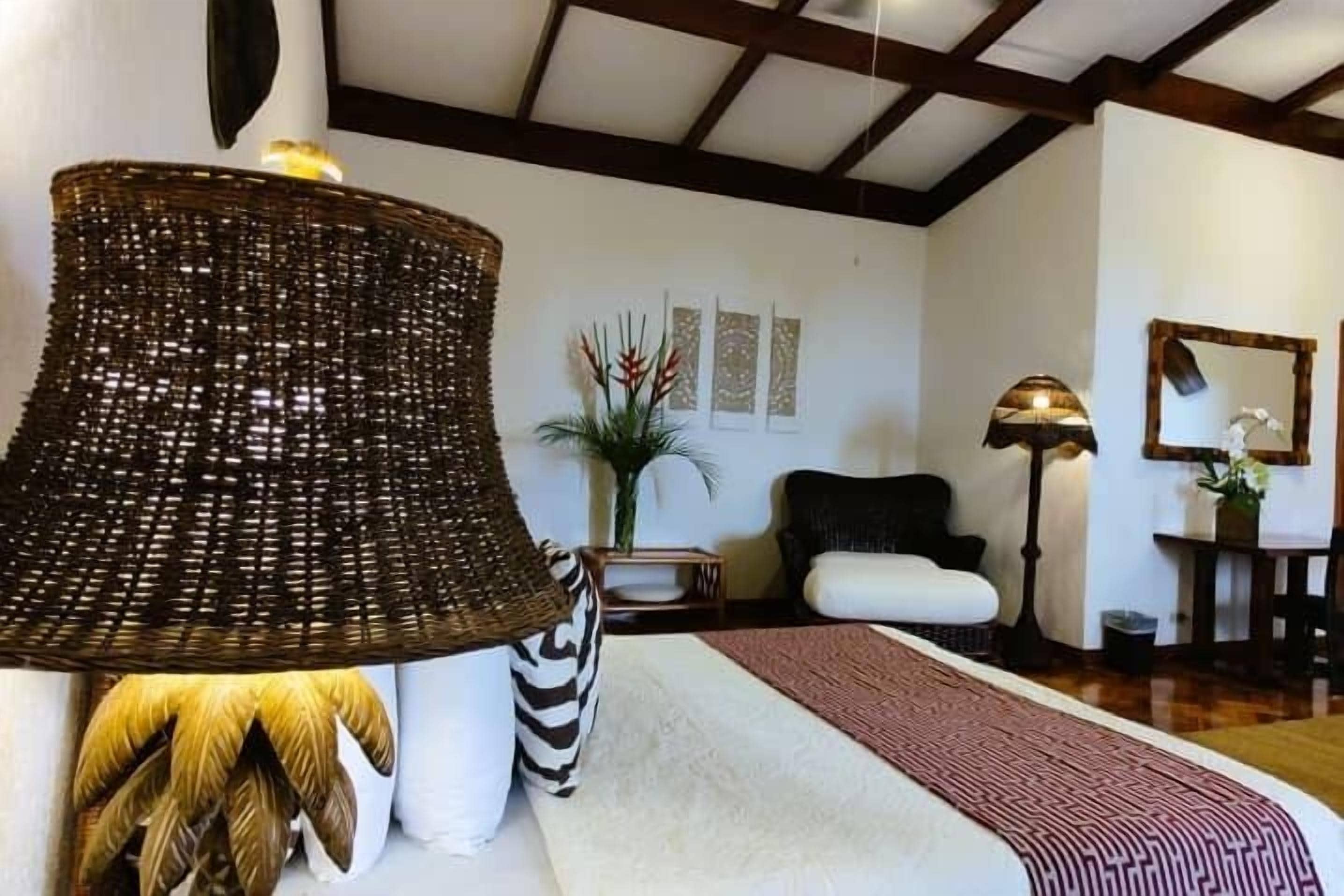 Une pièce avec une grande lampe en fibres tressées, un canapé blanc, un tapis à motifs et un miroir au mur.