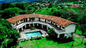 A two-story house with a swimming pool, surrounded by lush greenery and a hilly landscape. - Canal Grande Lodge (Piedades)