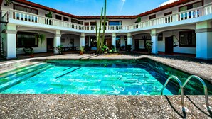 A pool area with a clear blue pool, surrounded by a white building with red-tiled roofs and multiple balconies. - Canal Grande Lodge (Piedades)