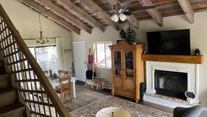 Un salón espacioso con chimenea, un televisor grande y techo de madera.
