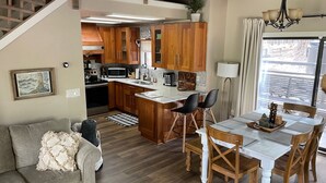 Una cocina moderna con armarios de madera, una isla central y una zona de comedor con mesa y sillas.