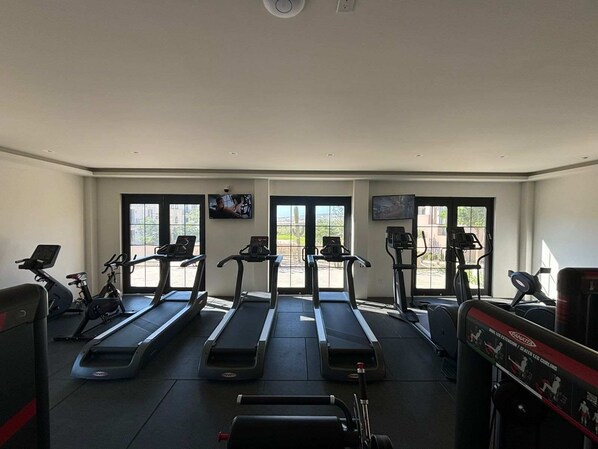 Un gimnasio con cintas de correr, bicicletas estáticas y máquinas de pesas.