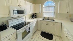 A kitchen with white cabinets, a stove, microwave, and a sink. - Beautiful, Spacious condo in the center of MB (Myrtle Beach)