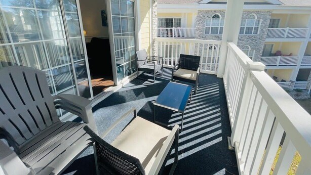 A balcony with outdoor furniture, a sliding glass door, and a view of neighboring buildings. - Beautiful, Spacious condo in the center of MB (Myrtle Beach)
