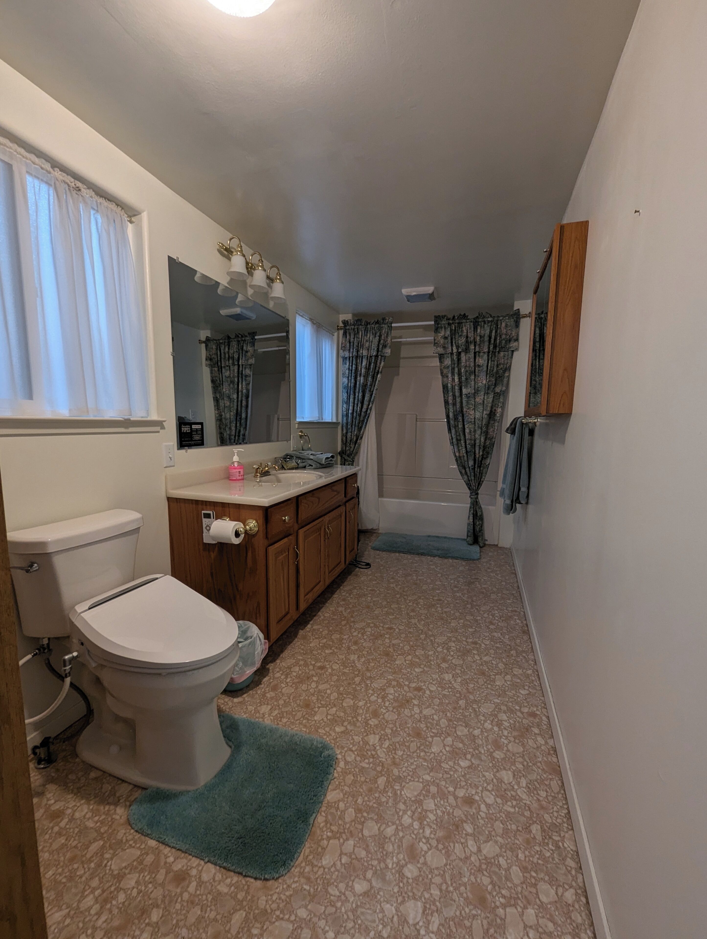 Ein Badezimmer mit Toilette, Waschbecken, Spiegel und Dusche.