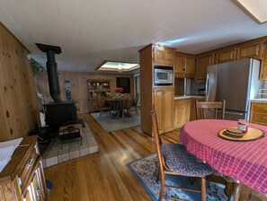 Un interior acogedor de cabaña con comedor, cocina y estufa de leña.