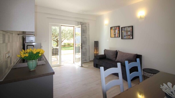 A modern kitchen with a dining area, a sofa, and a table with chairs. - Holiday apartment with barbecue and air conditioning (Poreč)