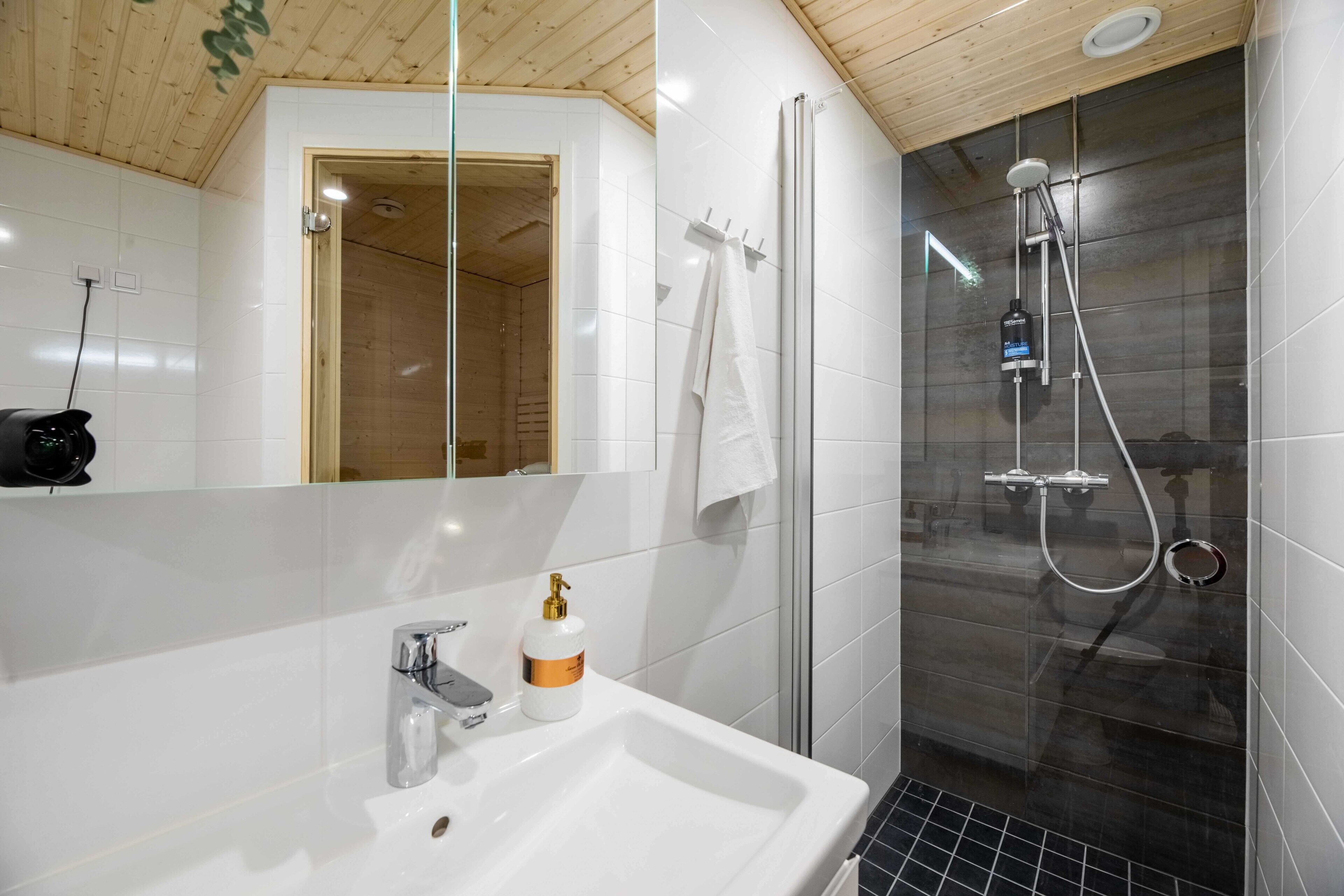 Un baño moderno con ducha de vidrio, lavabo blanco y espejo.